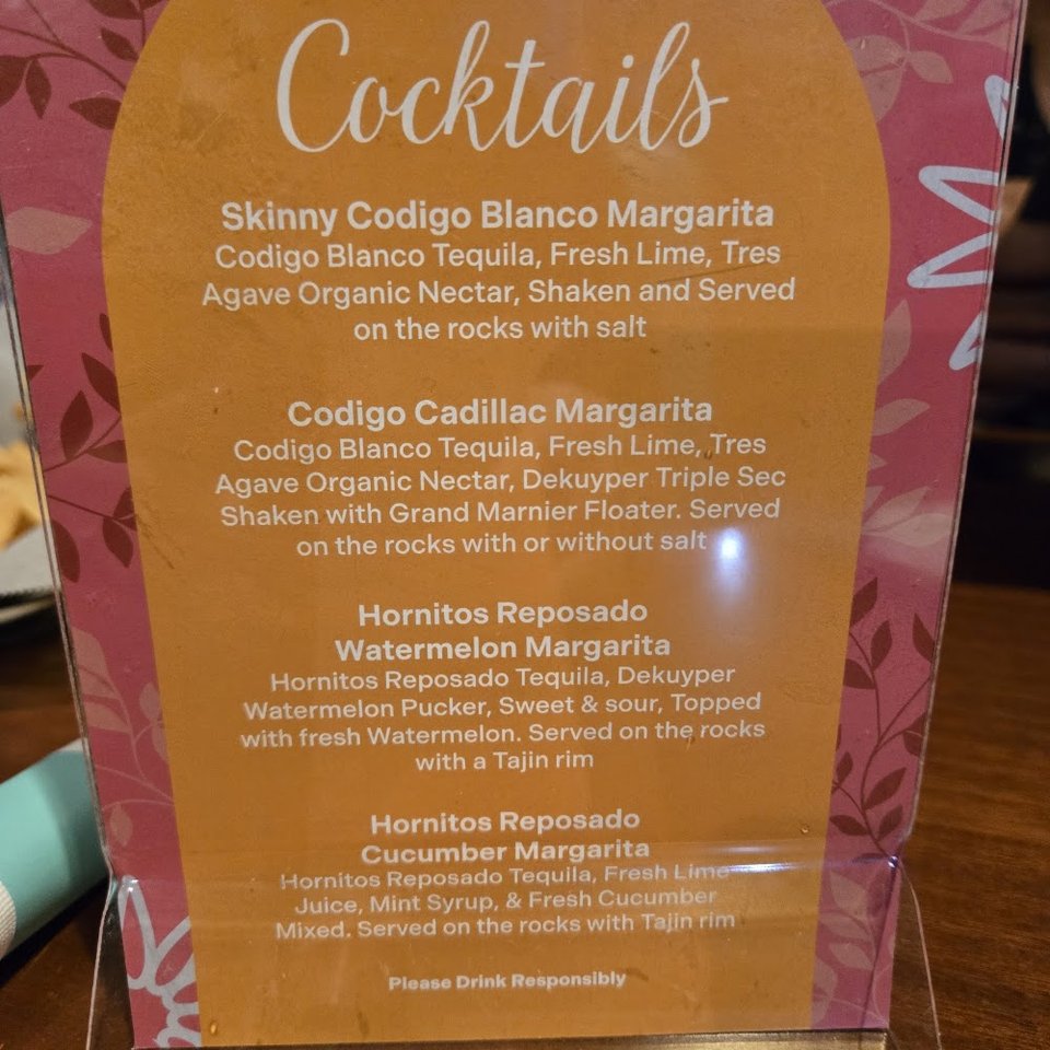 Close-up of menu items beside margaritas and happy hour.